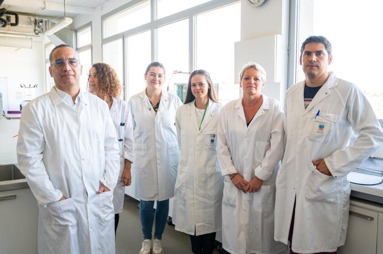 Une équipe de laborantins avec des blouses blanches pose pour une photo